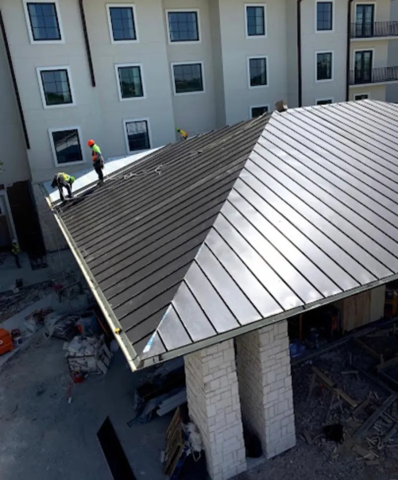 Crew installing standing seam metal roof panels on a commercial project in McKees Rocks